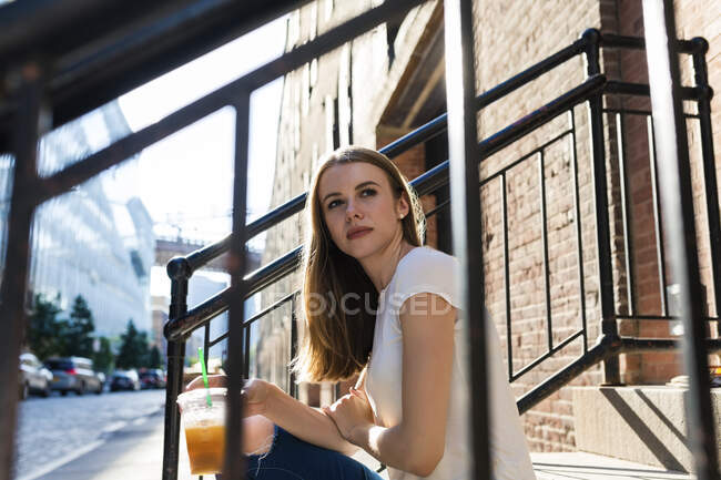 Junge Frau erkundet New York City, sitzt auf der Treppe und trinkt Kaffee — Stockfoto