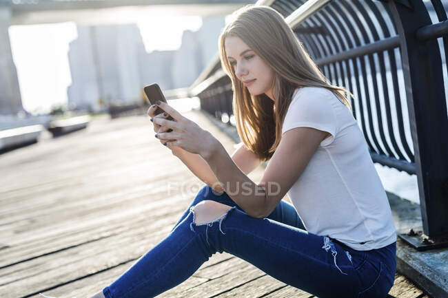 Young woman exploring New York City, ltaking a break, using smartphone — Stock Photo
