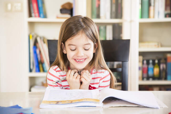 Retrato de niña feliz haciendo la tarea - foto de stock