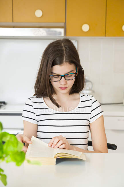 Дівчинка читає книжку на кухні. — стокове фото