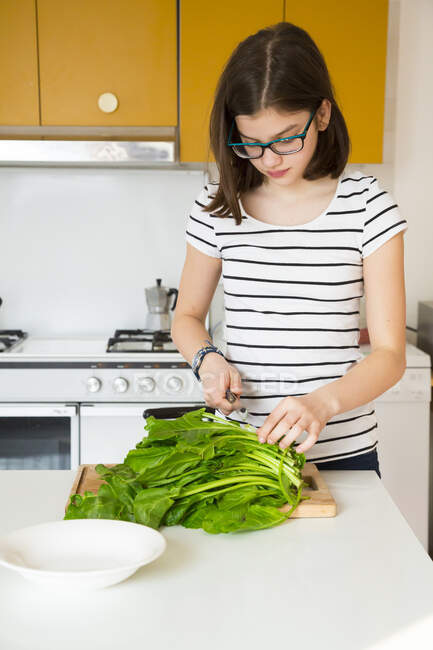 Ragazza che taglia verdure in cucina — Foto stock