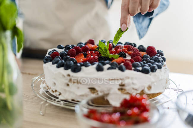 Giovane donna che prepara una torta alla panna con frutta fresca — Foto stock