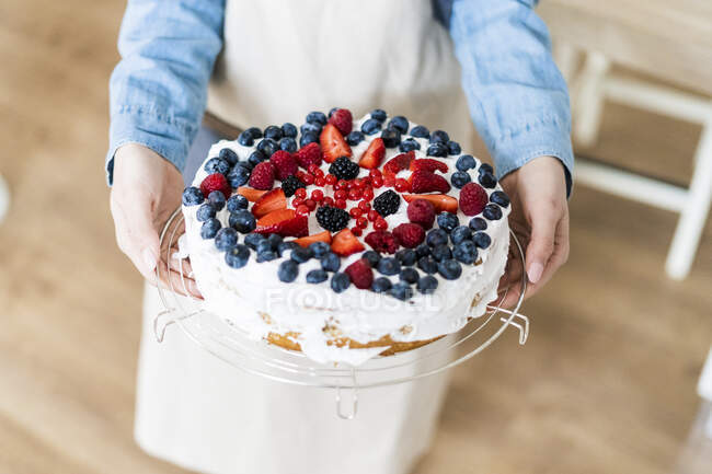 Giovane donna shwoing una torta alla panna con frutta fresca — Foto stock