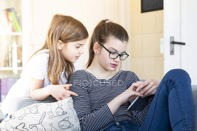 Dos hermanas mirando la tableta digital en casa - foto de stock
