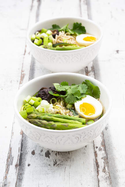 Two bowls of Ramen soup with egg, green asparagus, noodles, shitake mushroom and spring onions — Stock Photo
