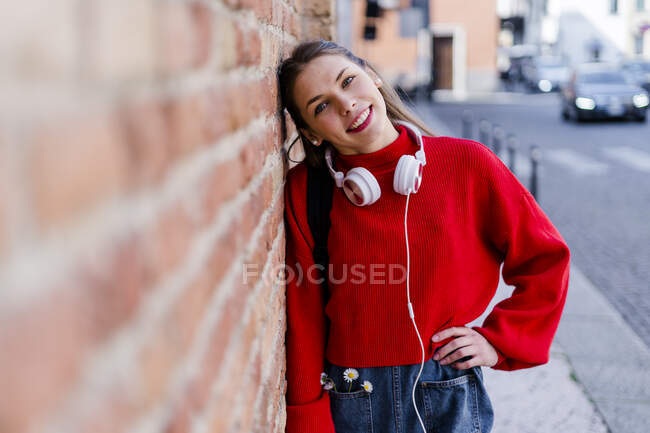 Молодая женщина в красном свитере, наушниках в Вероне — стоковое фото