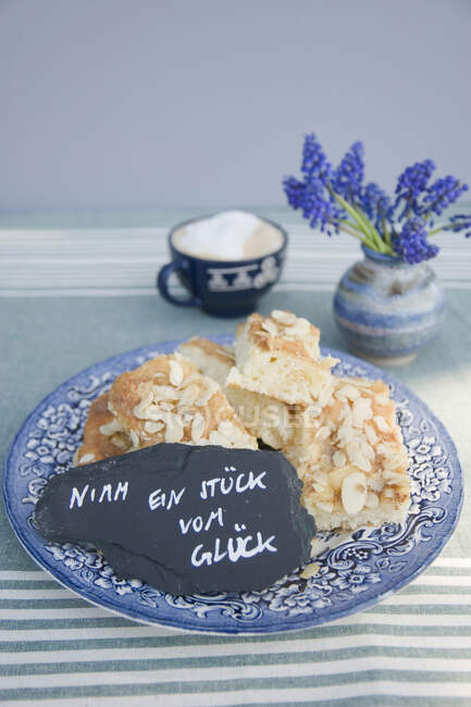 Assiette avec des morceaux de gâteau au beurre et un dicton manuscrit sur une ardoise — Photo de stock