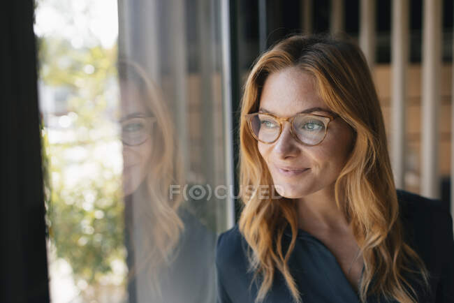 Portrait de femme d'affaires souriante regardant par la fenêtre — Photo de stock