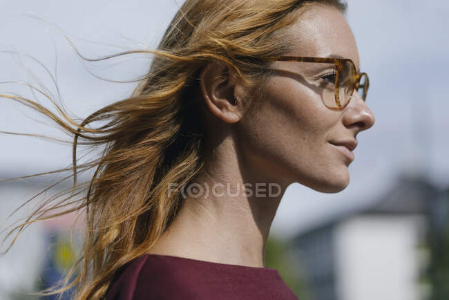 Profile of young woman with glasses and windswept hair — Stock Photo
