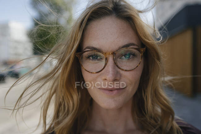 Ritratto di giovane donna sicura di sé con occhiali e capelli spazzati dal vento — Foto stock