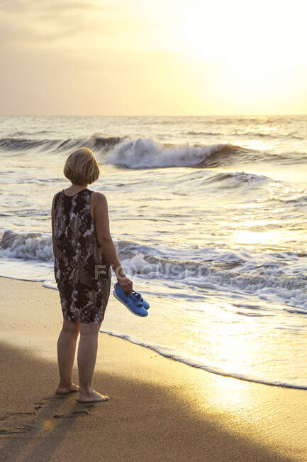 Italien, Sizilien, Seniorin genießt den Sonnenuntergang am Strand — Stockfoto