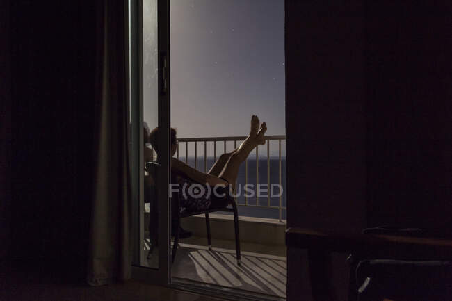 Grecia, donna seduta sul balcone di notte con vista sul mare — Foto stock