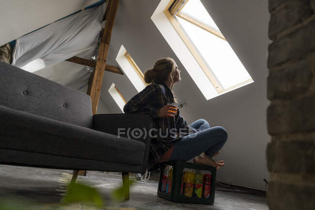 Junge Frau sitzt auf Kiste mit Softdrinks und schaut aus dem Fenster — Stockfoto