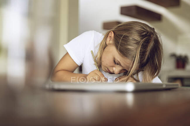 Menina sentada à mesa escrevendo em diário — Fotografia de Stock