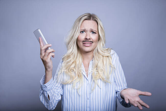 Portrait de demander femme blonde avec fausse moustache et smartphone — Photo de stock