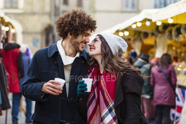 Счастливая молодая пара с горячими напитками на Рождественском базаре — стоковое фото