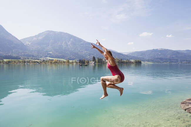 Austria, Alps, Salzburg, Salzkammergut, Salzburger Land, Wolfgangsee, woman jumping into lake — Stock Photo