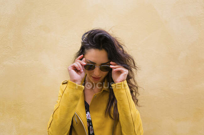 Retrato de jovem mulher vestindo jaqueta de couro amarelo e óculos de sol — Fotografia de Stock