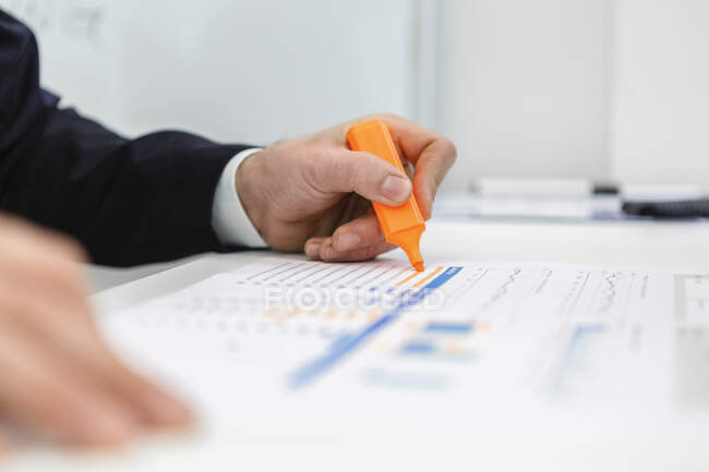 Close-up de empresário usando iluminador em um relatório na mesa no escritório — Fotografia de Stock
