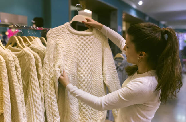 Жінка тримає светр у вінтажному бутіку. — стокове фото