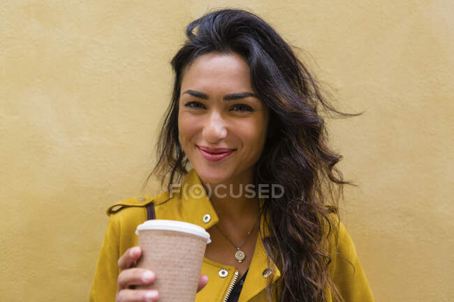 Retrato de mulher jovem usando jaqueta de couro amarelo, segurando xícara de café — Fotografia de Stock