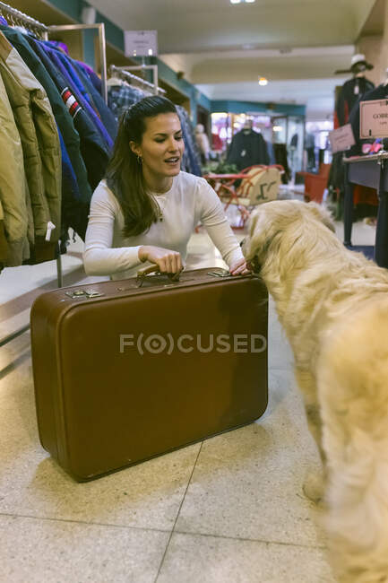 Woman with dog and old-fashioned suitcase in a vintage boutique — Stock Photo