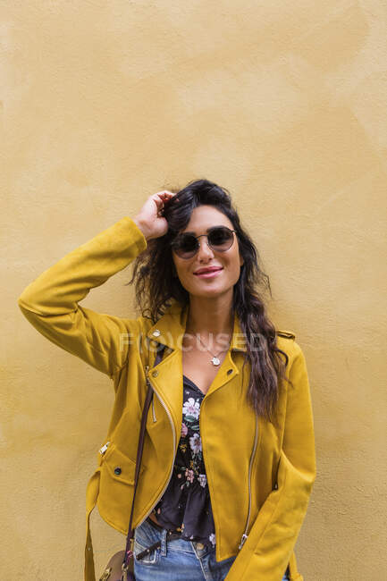 Ritratto di giovane donna con giacca di pelle gialla e occhiali da sole — Foto stock