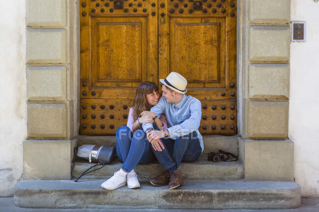 Молода пара сидить на сходах і робить перерву на міській подорожі. — стокове фото