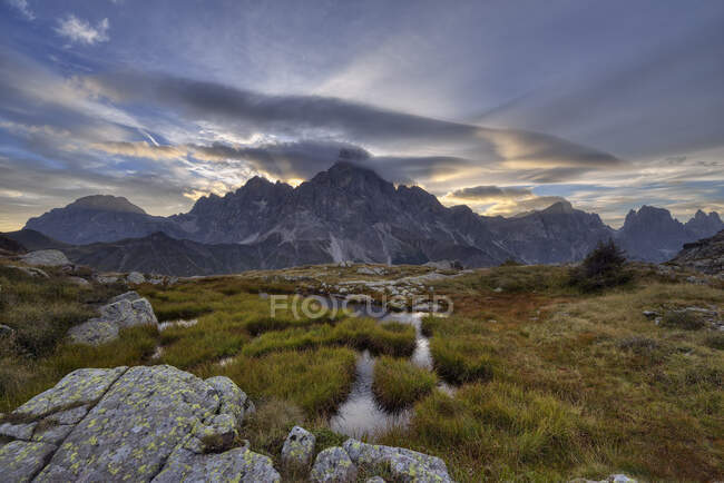 Italy, Dolomites, Passo Rolle, Trentino, Pale di San Martino Mountain group with the mountain Cimon della Pala with small pond at sunrise — стокове фото