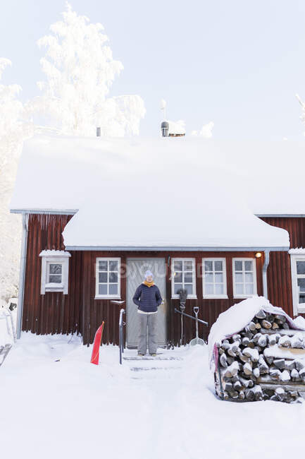 Finlandia, Kuopio, mujer de pie frente a la granja en invierno - foto de stock