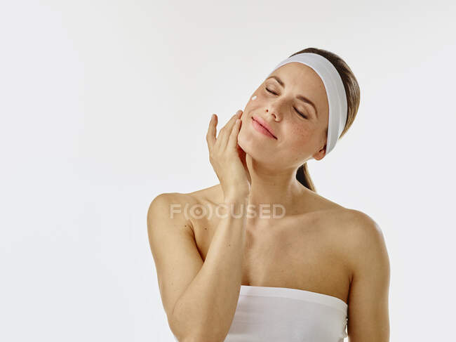 Mujer joven aplicando crema facial en su cara - foto de stock
