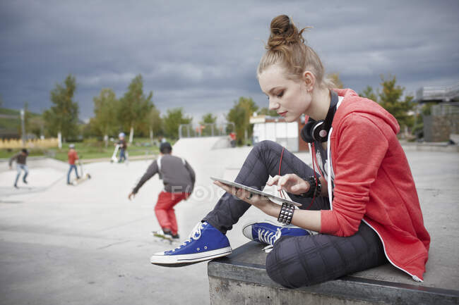 Teenage girl using a tablet at a skatepark — Stock Photo