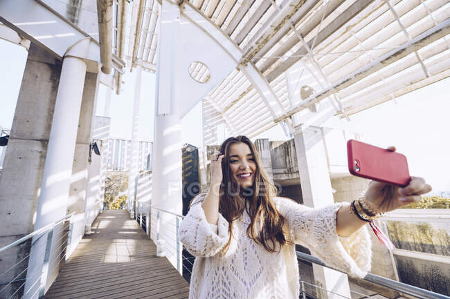 Felice giovane donna prendendo un selfie su un ponte — Foto stock