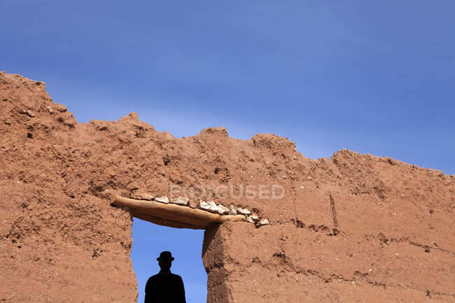 Марокко, Айт-Бен-Хадду, силуэт человека в котелке под стеной из глины — стоковое фото