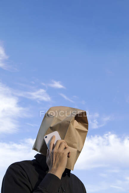 Homem com saco de papel acima da cabeça falando no celular — Fotografia de Stock