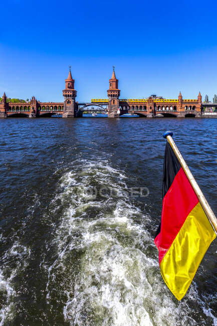 Alemanha, Berlim, Ponte Oberbaum e bandeira alemã em barco de excursão no Rio Spree — Fotografia de Stock