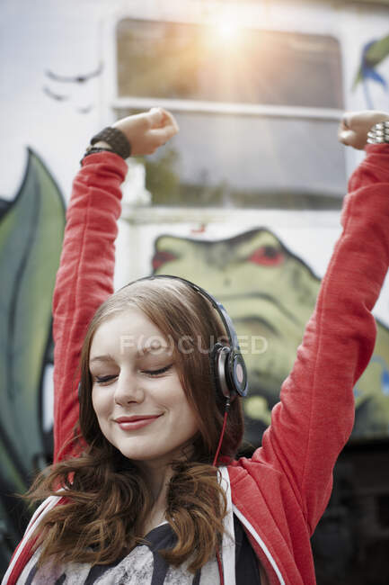 Retrato de una adolescente con auriculares en un vagón de tren pintado - foto de stock