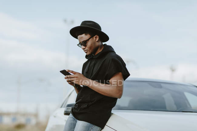 Portrait of a young man sending an email with the phone — Stock Photo