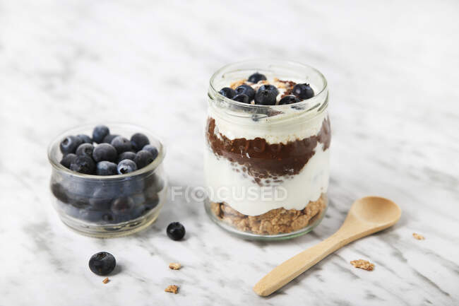 Jar of chia pudding parfait with chocolate and yoghurt with blueberries and granola — Stock Photo