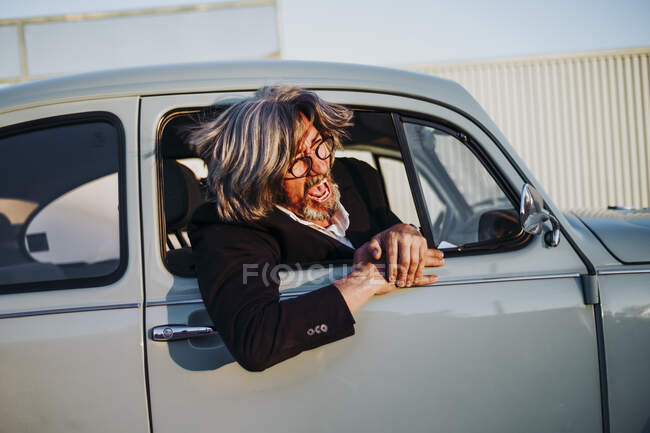 Senior homme penché par la fenêtre de la voiture vintage criant — Photo de stock