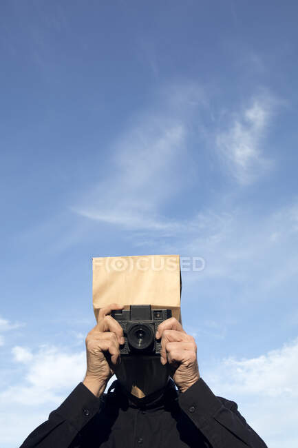 Человек с бумажным пакетом над головой фотографирует — стоковое фото