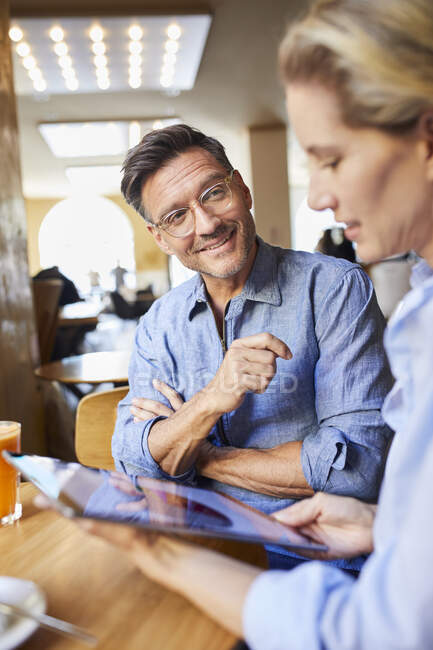 Hombre y mujer sonrientes con la tableta en un café - foto de stock