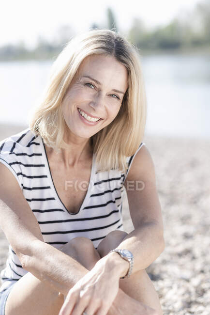 Портрет счастливой зрелой женщины, сидящей на берегу реки — стоковое фото