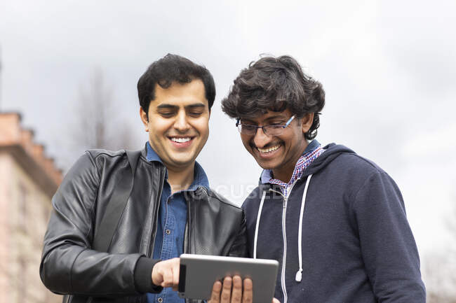 Portrait of smiling friends using mini tablet outdoors — Stock Photo