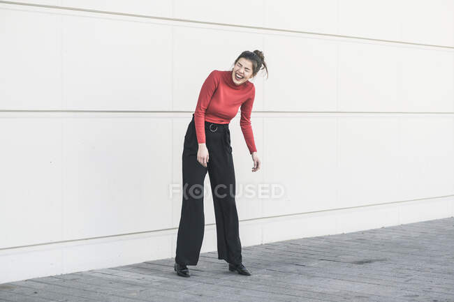 Ridendo giovane donna in piedi davanti a un muro — Foto stock