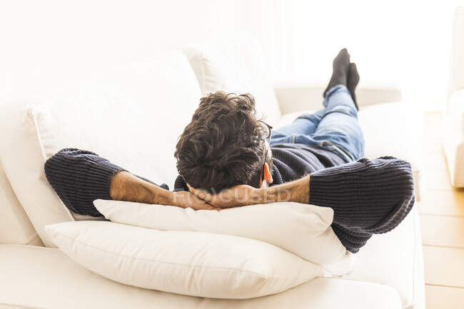 Вид сзади молодого человека, отдыхающего на диване дома — стоковое фото