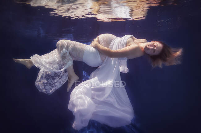 Femme enceinte portant une robe blanche sous l'eau — Photo de stock