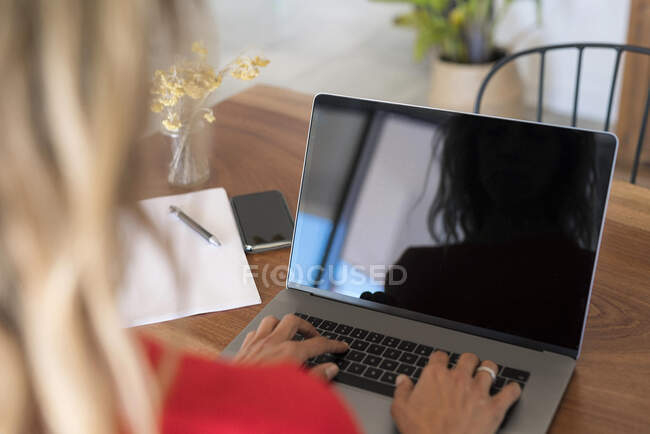 Primo piano della donna che utilizza il computer portatile sul tavolo di legno a casa — Foto stock