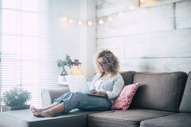 Жінка використовує ноутбук на дивані. — стокове фото