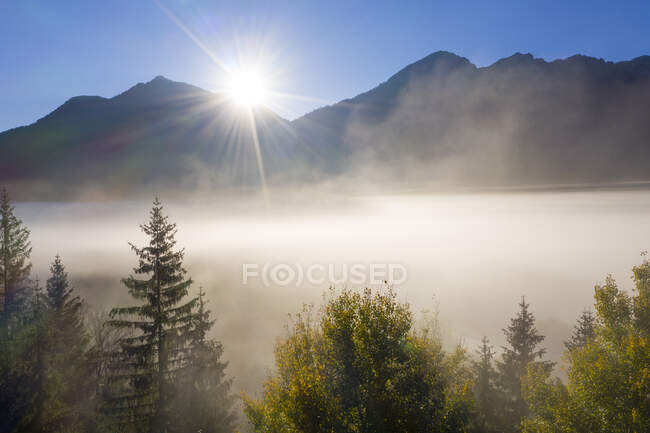 Germany, Upper Bavaria, Isarwinkel, Aerial view of Upper Isar Valley near Wallgau, Karwendel mountains in the background, against the sun — Stock Photo